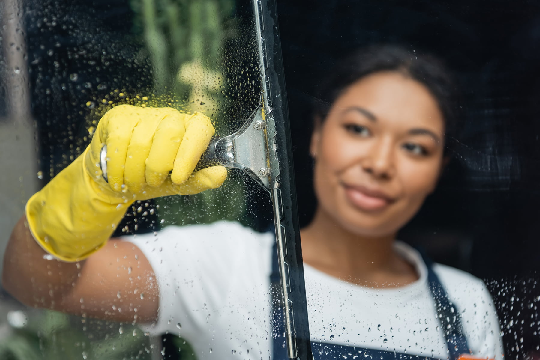 Blurred,Woman,In,Rubber,Glove,Cleaning,Glass,With,Window,Wiper blurred woman in rubber glove cleaning glass with window wiper
